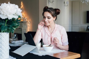 Kadın kahvaltı Hububat Ürünleri ve süt ve tablet bakar