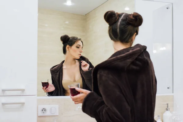 Женщина в коричневом удобном халате в ванной комнате — стоковое фото