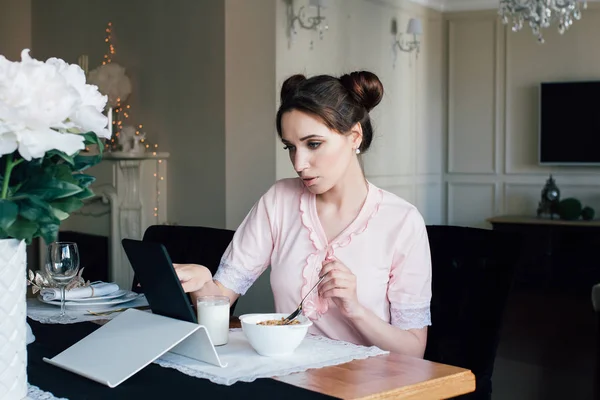 Vrouw ontbijten met granen en melk en kijkt naar Tablet PC — Stockfoto