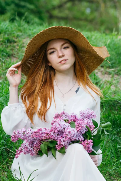 Rothaarige Mädchen mit einem Strauß Flieder in einem Frühlingsgarten — Stockfoto