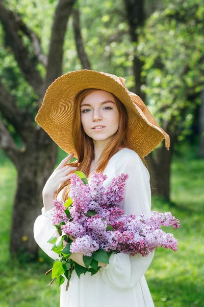 Rothaarige Mädchen mit einem Strauß Flieder in einem Frühlingsgarten — Stockfoto