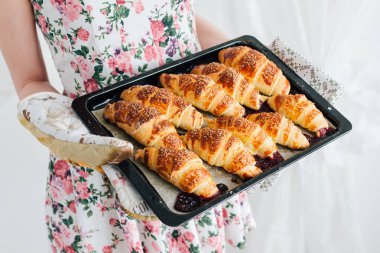 Bir pişirme levha hazır kruvasan tutan ev kadını