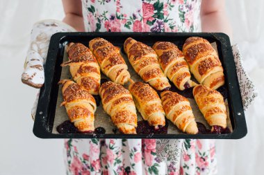 Bir pişirme levha hazır kruvasan tutan ev kadını