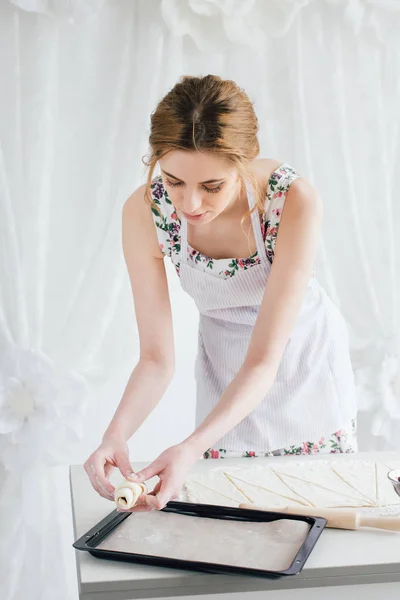 Nuori kaunis nainen valmistelee kotitekoisia croissanteja — kuvapankkivalokuva