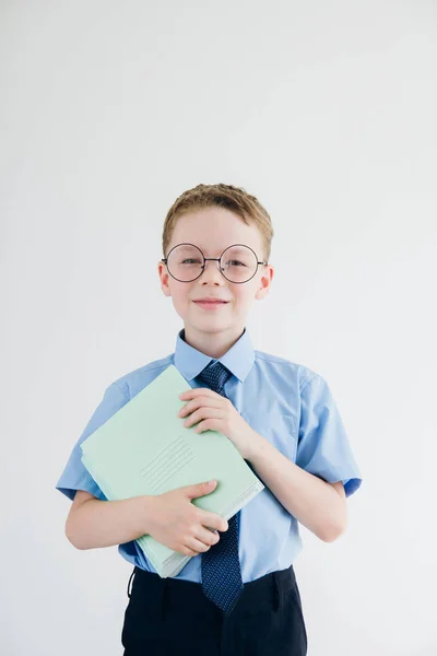 Школьник в школьной форме и очках, держит стопку бумаги — стоковое фото