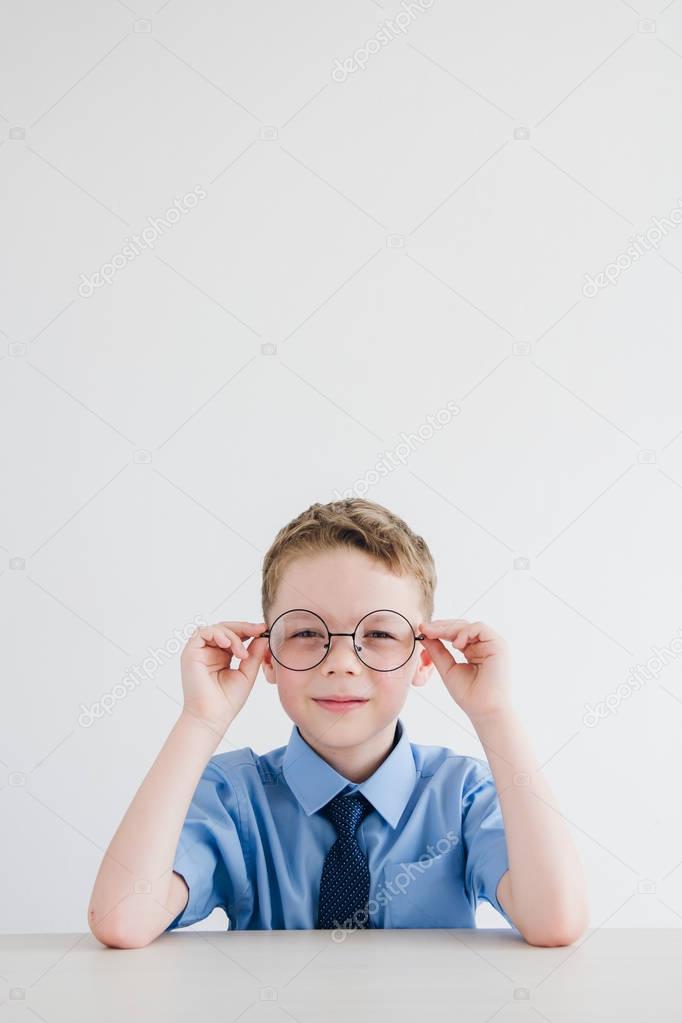 Schoolboy in school uniform and glasses sitting at the Desk