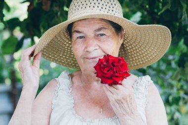 Yaşlı bir kadın ile bir kırmızı gül portresi. Tonlama. Seçici 