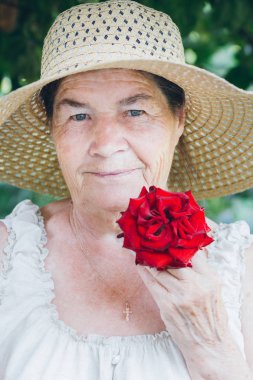 Yaşlı bir kadın ile bir kırmızı gül portresi. Tonlama. Seçici 
