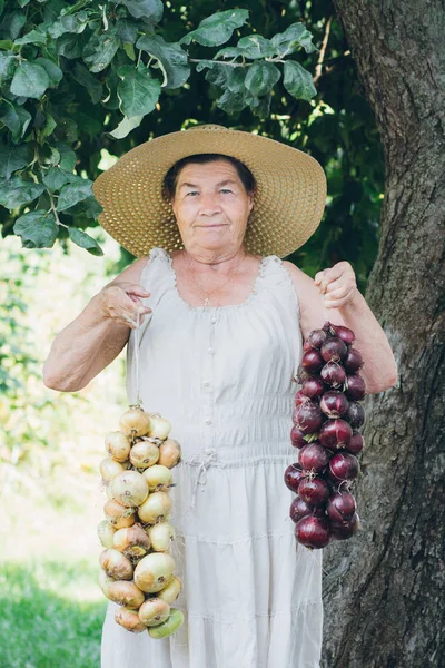 Bir soğan tutan şapkalı yaşlı bir kadın portresi