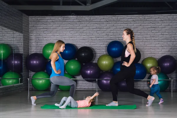 İki genç spor anne ve bebek kız yapmak egzersizleri birlikte