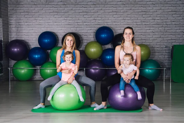 İki genç spor anne ve bebek kız yapmak egzersizleri birlikte