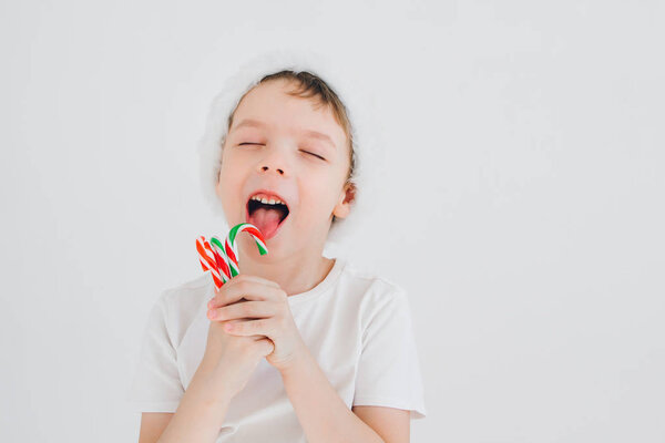 Boy in red Santa hat holding a candy cane 