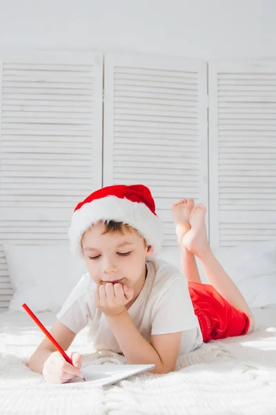 Boy in a red cap writes a letter to Santa — Stock Photo, Image