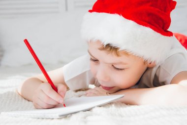 Kırmızı bere içindeki çocuk Noel Baba'ya bir mektup yazar