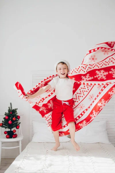 Мальчик прыгает на кровати, покрытой одеялом — стоковое фото