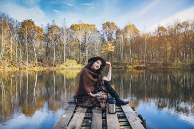 Bir ahşap köprü bir göl kenarında çay içme kız