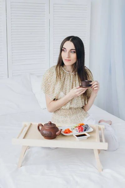 Woman drinking green tea and eating sushi