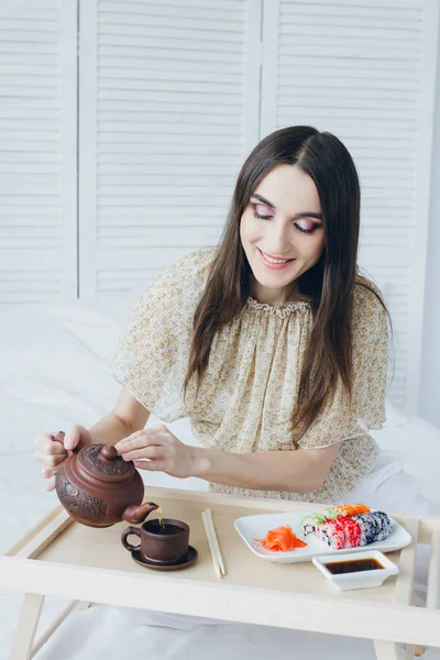 Woman drinking green tea and eating sushi