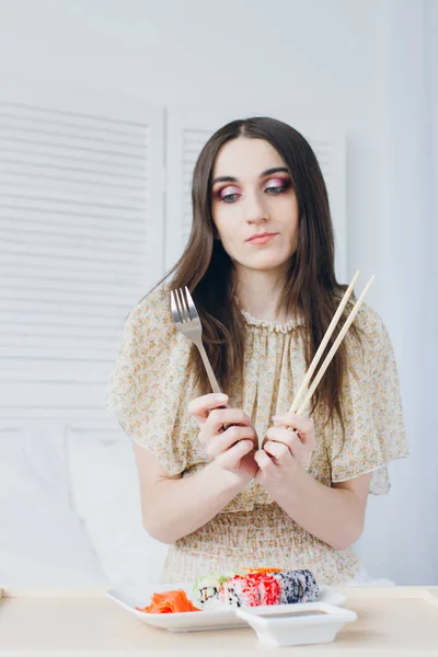 Kvinde vælger i hænderne på en gaffel og spisepinde . - Stock-foto