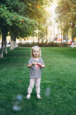 Küçük kız şişirmek sabun köpüğü'nın bahçesinde