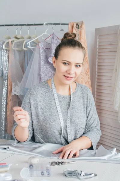 Young seamstress makes clothes cutting fabric