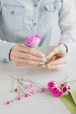 Çiçekçi Foamiran 'dan yapay çiçeklerle çelenk yapıyor.