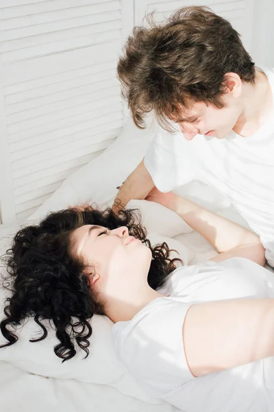 Любящая пара целуется обнимаясь в постели — стоковое фото