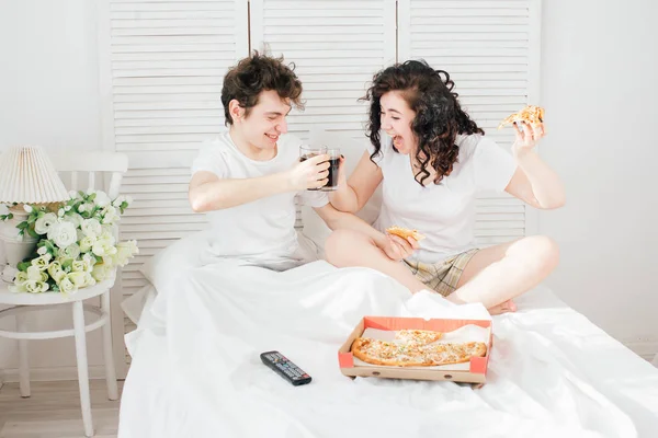 Coppia guardare la TV a letto e mangiare pizza — Foto Stock