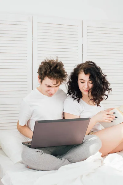 Guy werken voor een laptop, meisje leest een boek — Stockfoto