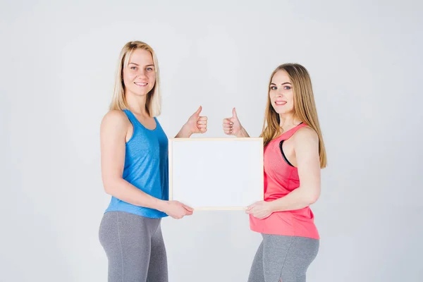 Две девушки держат рамку с объявлением — стоковое фото