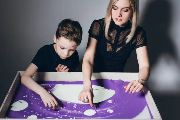Женщина и мальчик рисуют на интерактивном песчаном столе — стоковое фото