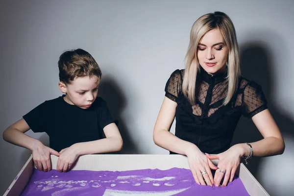 Женщина и мальчик рисуют на интерактивном песчаном столе — стоковое фото