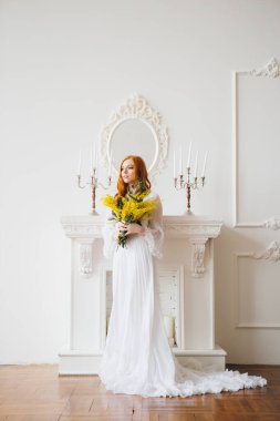 Uzun beyaz elbiseli bir Mimosa 'lı kızıl saçlı güzel bir kızın portresi. Bahar konseri. Tonlama.