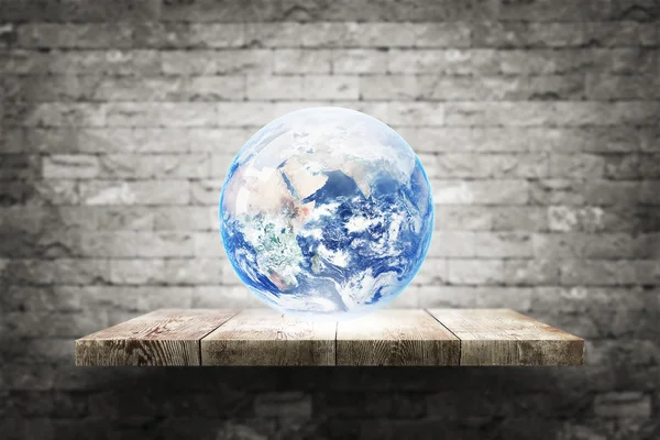 Earth globe on wood shelf over white brick background. — Stock Photo, Image