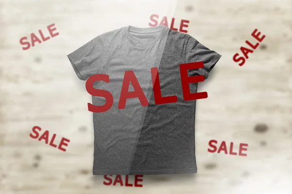 Grey shirt with inscription SALE over wood background — Stock fotografie
