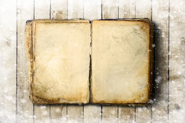 Старая книга с пустыми простынями и снежинками на деревянном фоне — стоковое фото
