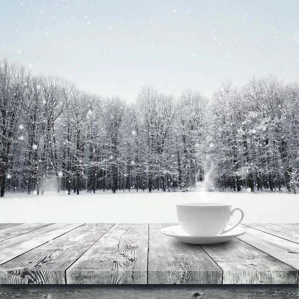 Гарячий напій у чашці на дерев'яному столі над зимовим снігом покрив ліс. Краса природа фон — стокове фото