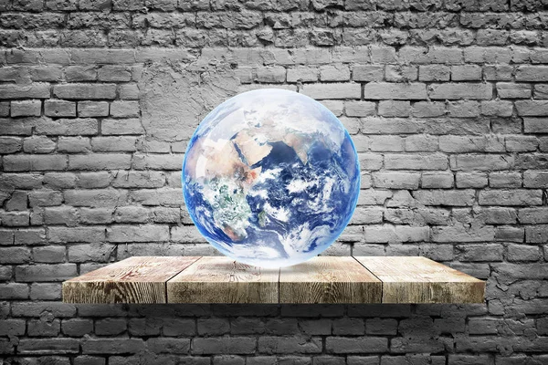 Earth globe op houten plank over witte bakstenen achtergrond — Stockfoto
