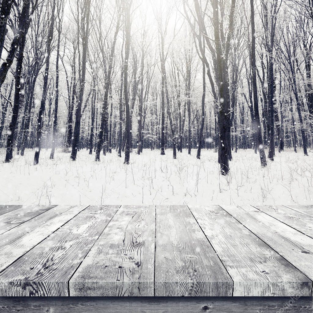 Wooden table over winter snow covered forest. Beauty nature background