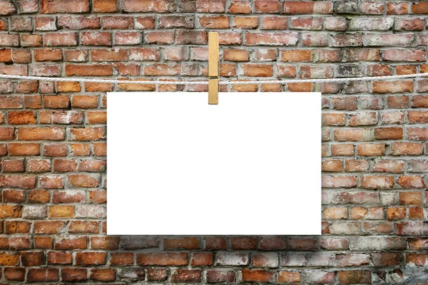 Photo frame with pin on rope over old aged brick wall background — Stock Photo, Image