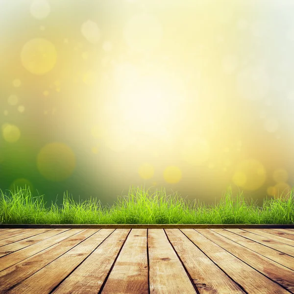 Frisches frühlingsgrünes Gras mit grünem Bokeh und Sonnenlicht und Holzboden — Stockfoto