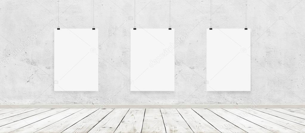 Tree white blank posters with binders in interior with concrete wall and wooden floor 