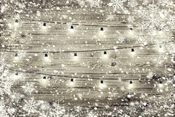 La textura de madera marrón con guirnalda y copos de nieve sobre ella . —  Fotos de Stock