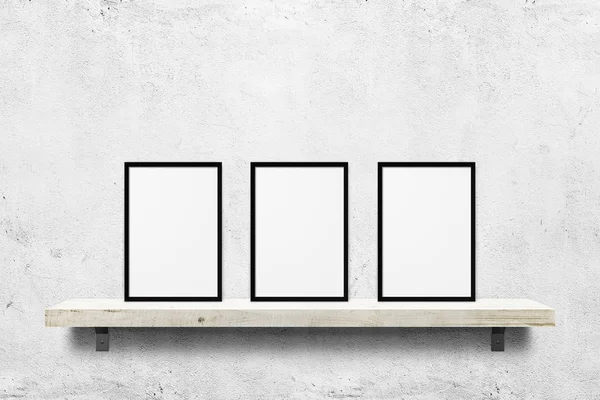 White blank photo frames mockup on shelf over white concrete wall background