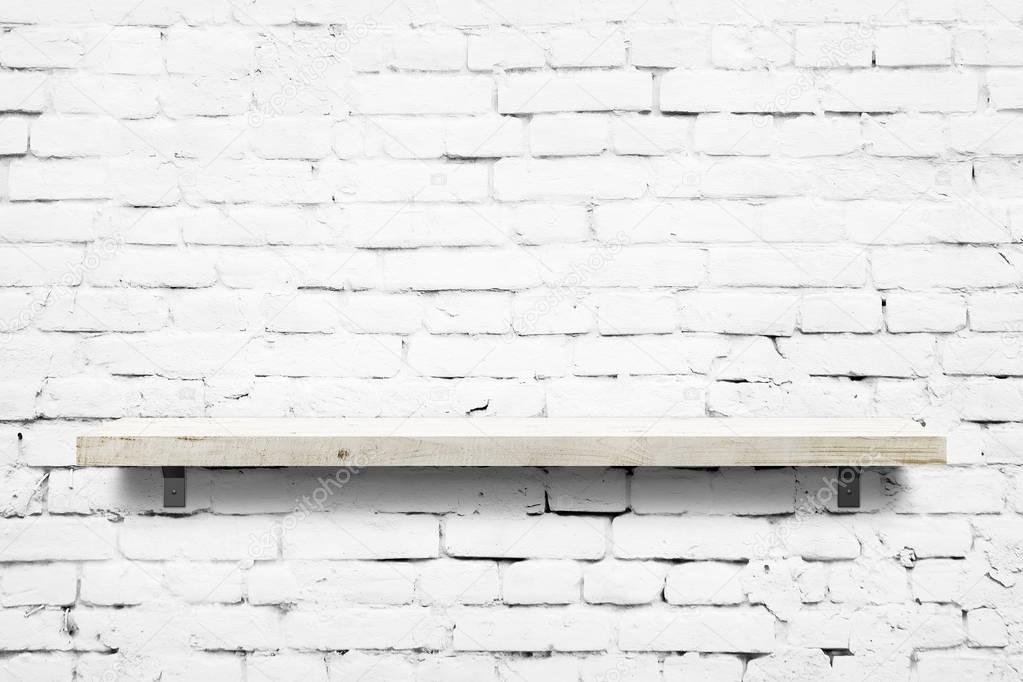 Wooden shelf over white brick wall background