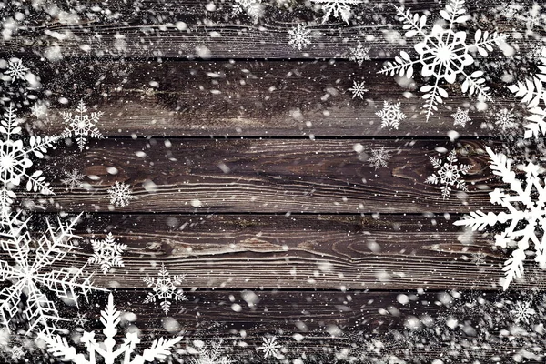 Die braune Holzstruktur mit Schneeflocken darüber. Winterlicher Hintergrund — Stockfoto