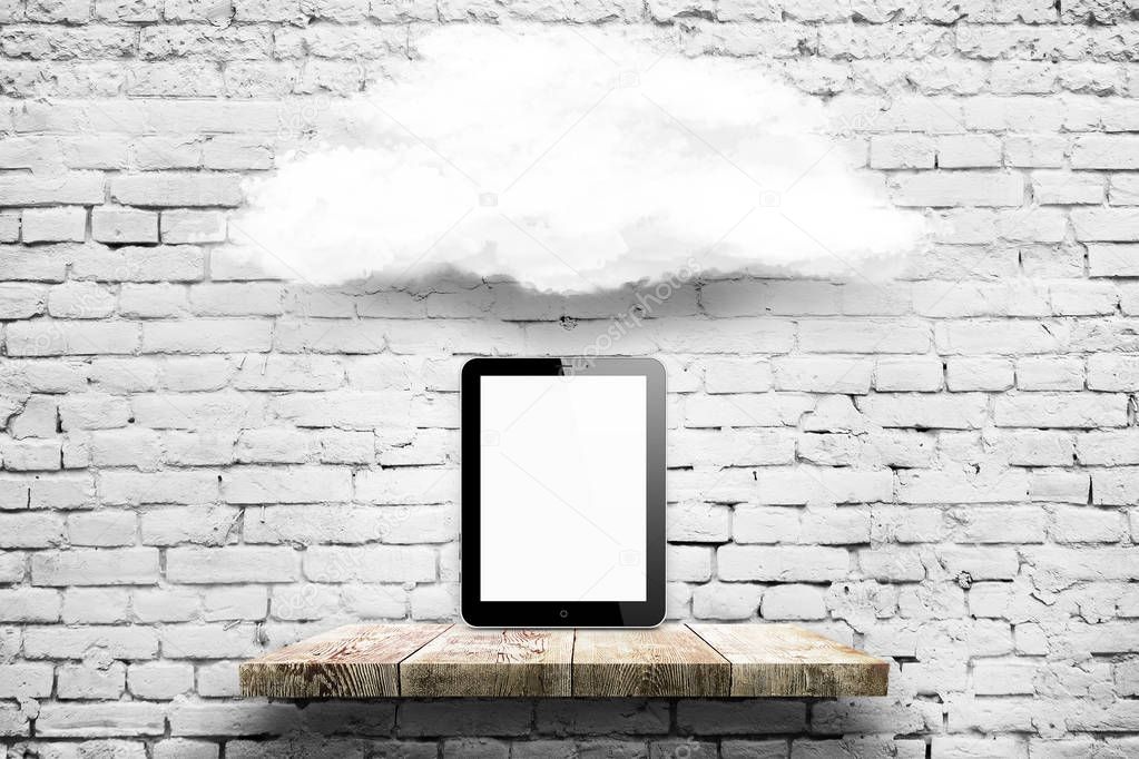 Tablet computer on wood shelf with cloud over white brick background.