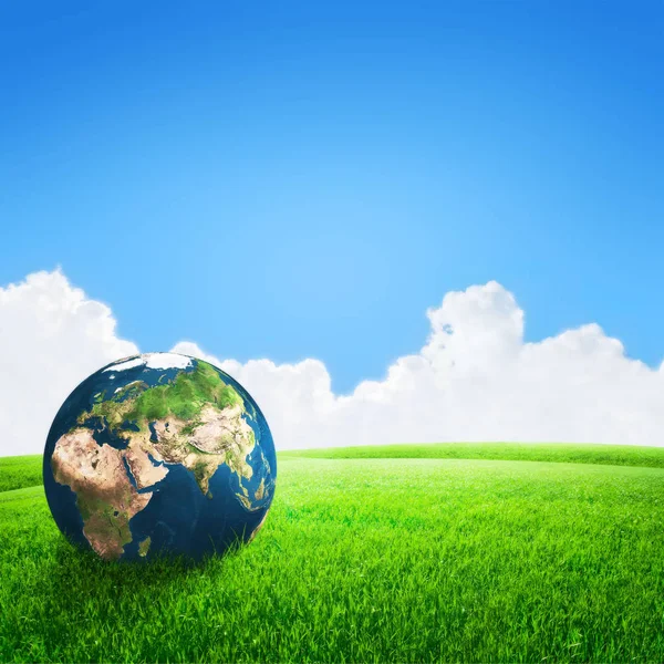 Κόσμο πλανήτη γη στο πράσινο χόρτο πεδίο και μπλε ουρανό φόντο — Φωτογραφία Αρχείου