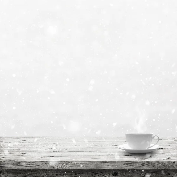 Bebida caliente en la taza en la mesa de madera sobre fondo de nieve de invierno —  Fotos de Stock