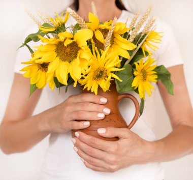 Beyaz t ile ahşap masa üzerinde bir seramik vazoda sarı ayçiçeği